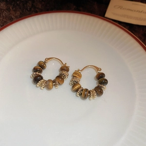 Detail of vintage gold earrings with tiger eye beads and metal spacers on a tray