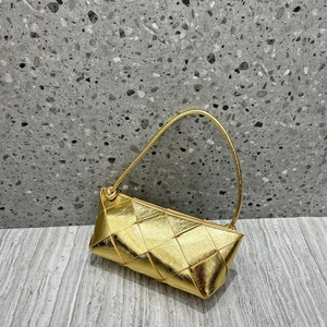 Detail of gold woven leather mini bag with metallic finish on a minimalist background