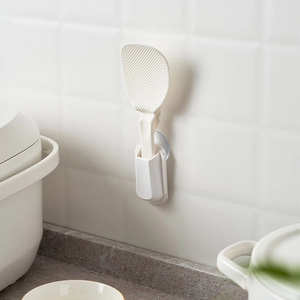 Japanese suction cup rice spoon holder in white plastic mounted on kitchen wall tiles