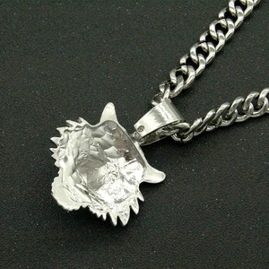 Macro detail of silver tone tiger head pendant with cubic zirconia on black texture