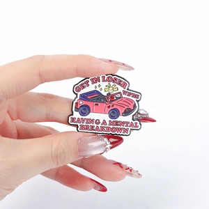 Pink cartoon car enamel pin with Get In Loser slogan held in hand on white background