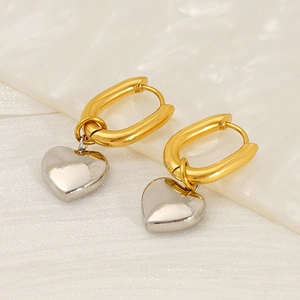 Macro detail of 18K gold-plated oval hoop earrings with silver heart charms on silk