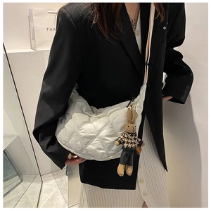 Detail of white quilted half-moon crossbody bag featuring a cute bunny doll charm