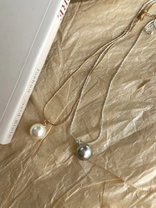 Detailed macro view of white and grey round pearl pendants on gold and silver snake chains