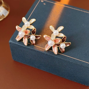 Macro detail of tricolor floral earrings with pearls and gold-plated metal edges