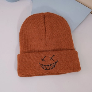 Detail view of the caramel knitted beanie showing thick ribbed texture and embroidered face
