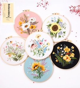 Detailed close-up of six floral DIY embroidery kits with wooden hoops on white background