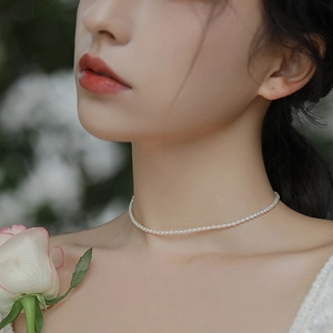 Close-up of minimalist pearl necklace on a woman's neck with elegant floral background