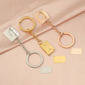Polished stainless steel envelope pendants in silver, gold, and rose gold on pink silk
