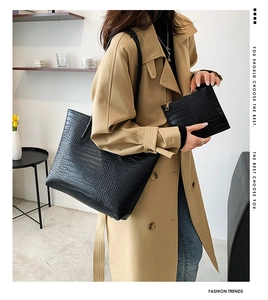 Detail of black crocodile texture tote bag and pouch set worn with a beige trench coat