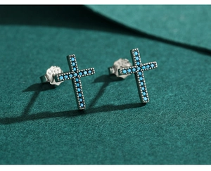 Macro detail of 925 silver cross stud earrings with turquoise stones on dark surface
