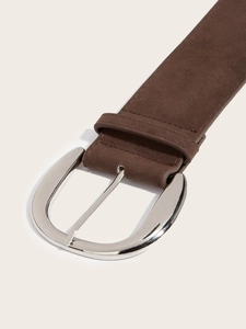Close-up of a vintage dark brown suede belt featuring a polished silver metal buckle