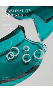 Detail of S925 sterling silver hoop earrings on broken glass texture with engraved logo