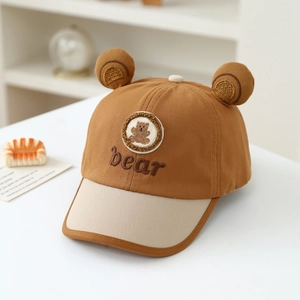 Detail of baby baseball cap with plush bear ears, brown contrast brim and embroidery