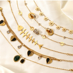 Detailed view of layered gold chain jewelry with heart charms and zircon on silk fabric