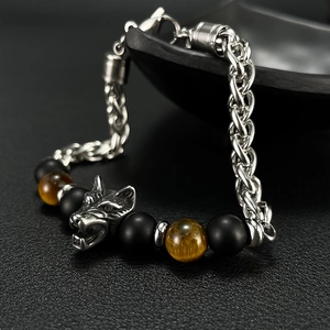 Macro view of men's tiger eye beads and metal wolf head charm on a stainless steel bracelet