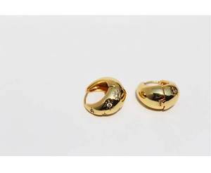 Macro detail of gold huggie earrings with star-shaped zircon inlays and polished finish