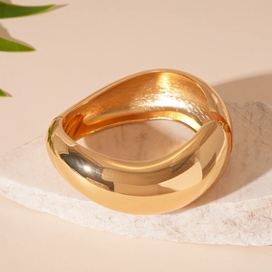 Detailed view of wide gold geometric bangle with mirror-polished finish and hinge detail