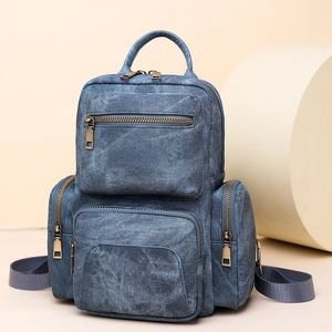 Detail of vintage denim blue PU leather backpack showing texture and metal zippers