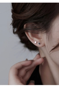 Macro shot of minimalist square S925 silver stud earrings with black and white accents