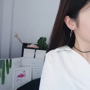 Silver cross pendant earring with chain on model showing a stylish minimalist look
