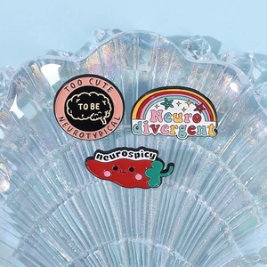 Three enamel pins with rainbow and pepper designs in a seashell glass dish on blue background