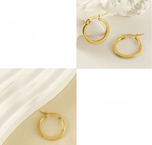 Macro shot of gold hoop earrings with vertical grooves and polished finish on a cream base