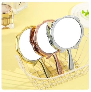 Close-up of three rose-shaped hand mirrors in gold, rose gold and silver metallic finishes