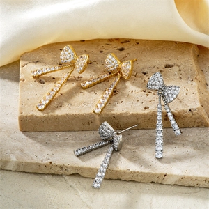 Exquisite Schleifen-Quastenohrringe in Gold und Silber mit Zirkon-Besatz auf Steinhintergrund