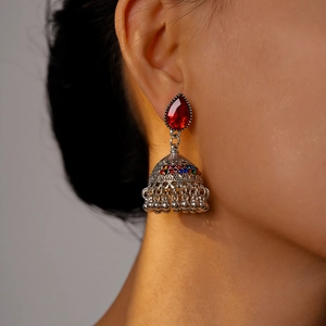 Detailed view of vintage jhumka earrings with ruby water drop pendant and silver finish
