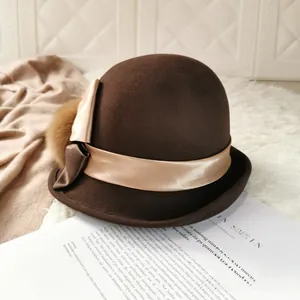 Close-up of wool bowler hat with champagne satin bow and faux fur pompom detail