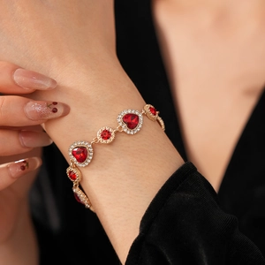 Dettaglio di un bracciale vintage dorato con cuori di rubino e accenti di diamanti