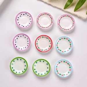 Top view of nine miniature resin plates with assorted colorful hand-painted patterns