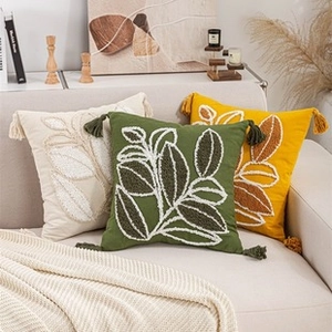Detail of premium embroidered throw pillows with botanical leaf patterns and tassels