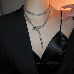 Detail of silver snake necklace with green gemstone eyes and flexible mesh body