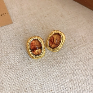 Macro detail of retro resin earrings with amber stone on beige linen background