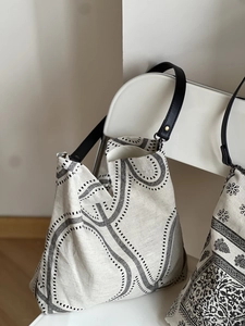 Detail of minimalist tote bag with black geometric lines hanging on a white chair