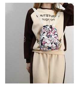 Detail showing mini butterfly print canvas backpack size on model against white wall