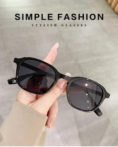 Close-up of stylish black frame sunglasses with dark grey lenses and simple fashion text