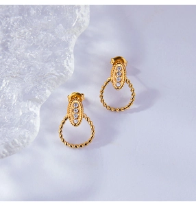 Macro detail of gold plated oval earrings featuring central crystals and rope texture
