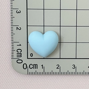 Close-up of a 2cm light blue macaron heart resin accessory measured with a ruler scale