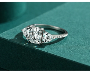 Macro shot of silver ring with emerald cut center stone and pear side diamonds