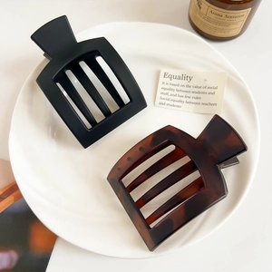 Matte black and tortoise shell square hair claw clips set on white ceramic tray