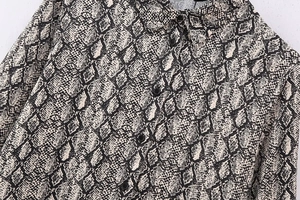 Detailansicht der Damenbluse mit Schlangenmuster, klassischem Kragen und schwarzen Knöpfen