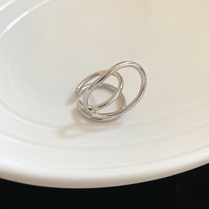 Macro detail of silver geometric double-layered open ring on a white ceramic plate