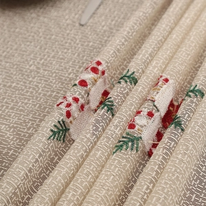 Close-up of festive Christmas embroidery with red berries and green pine on linen fabric