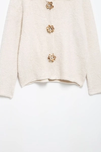 Détails des boutons fleurs sur le gilet en maille texturée blanc cassé doux