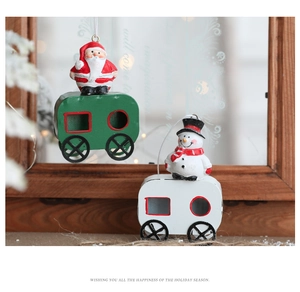 Detailed view of metal Santa and Snowman train ornaments on a festive wooden background