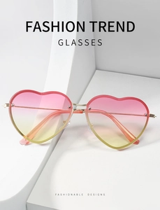 Close-up of pink gradient heart lenses with golden metal temples on geometric blocks