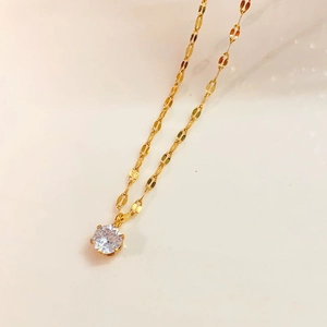 Close-up of a gold solitaire necklace featuring a brilliant round-cut zircon in a 6-prong setting